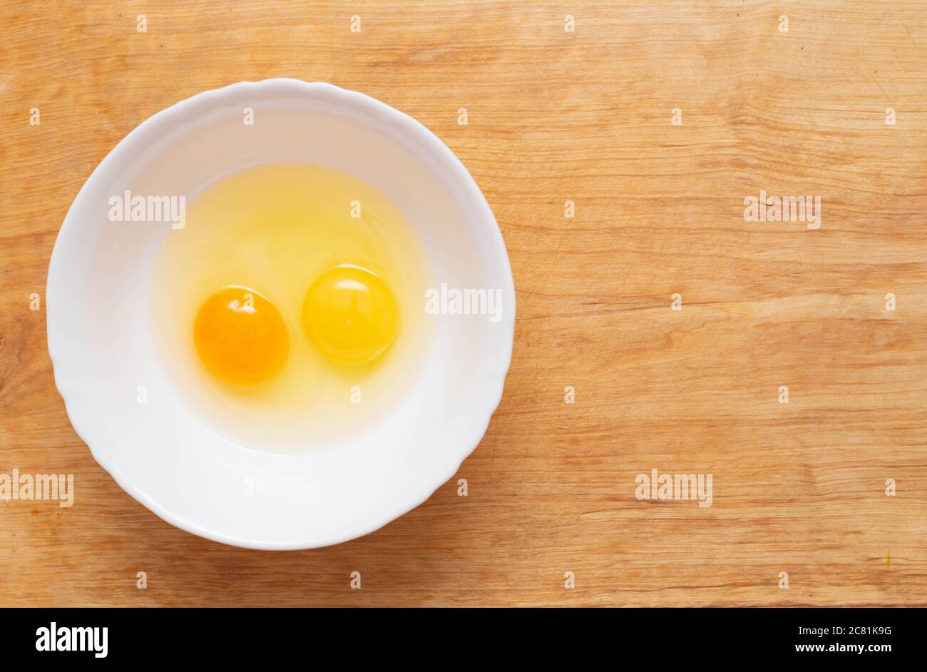 Two chicken eggs, homemade and factory, are broken in a glass plate. Difference concept of homemade natural eggs from store-bought, organic Stock Photo