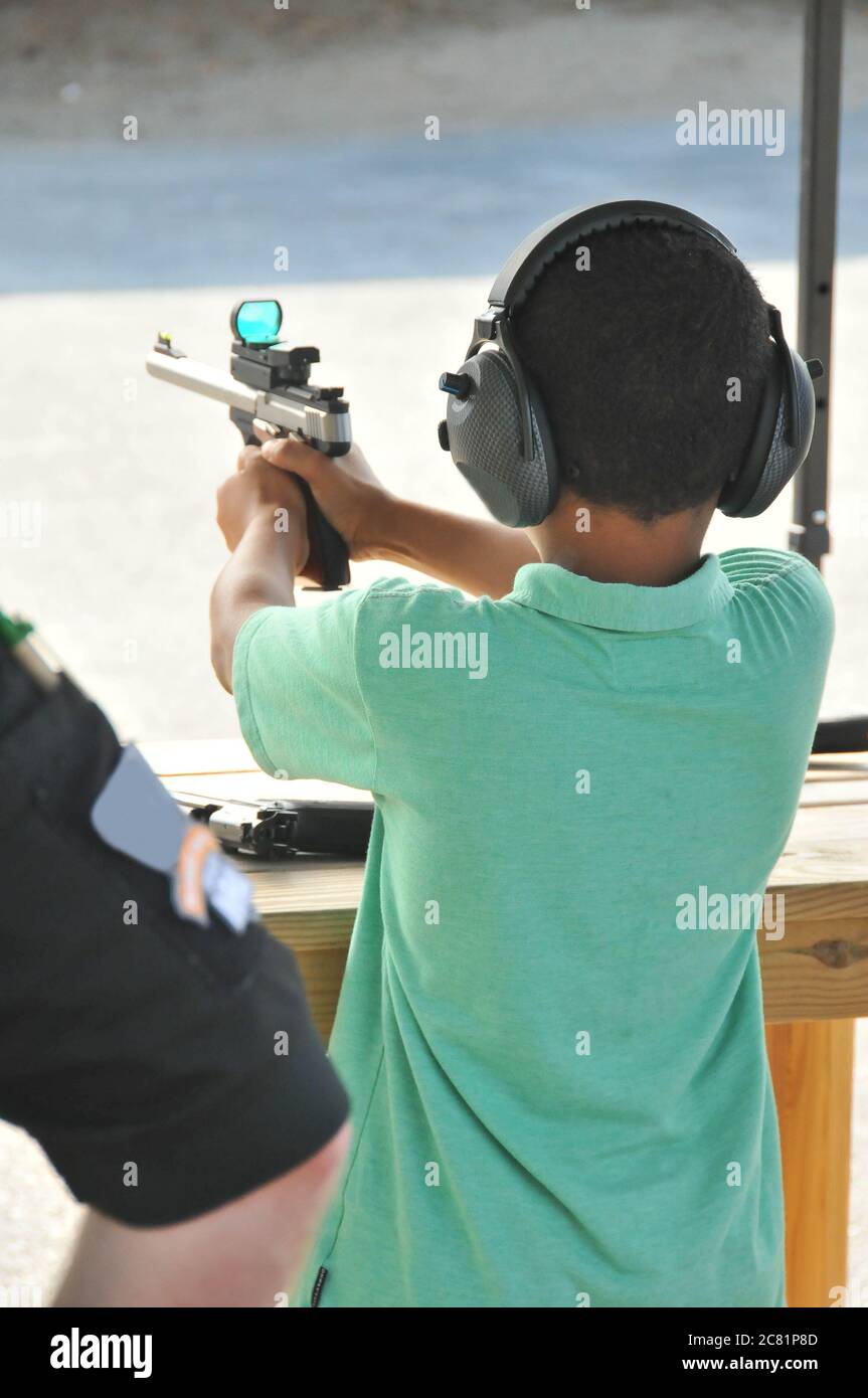 A young African-American boy takes careful aim at a target with a firearm. Stock Photo