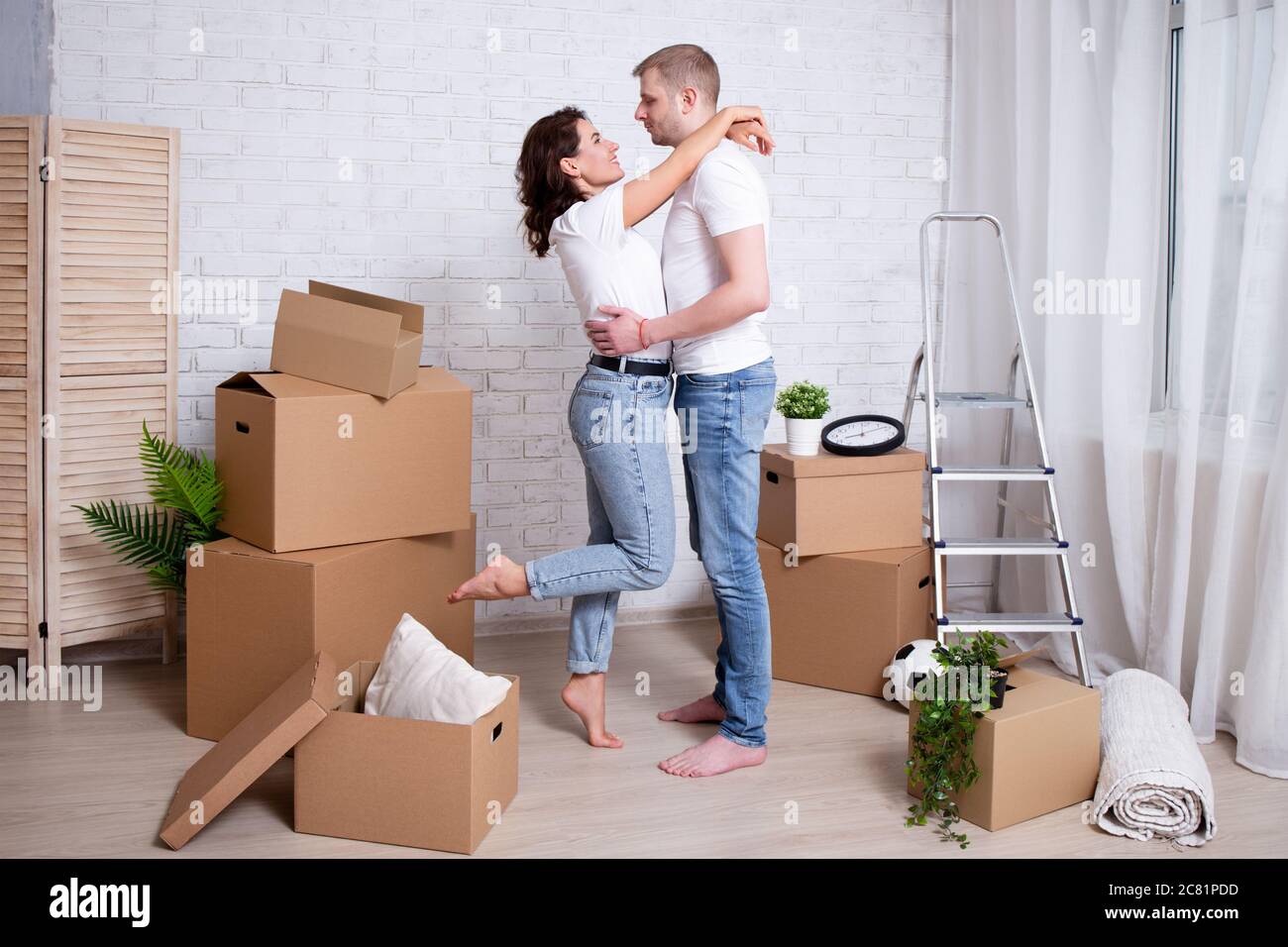 moving day - happy young couple embracing in their new house surrounded ...