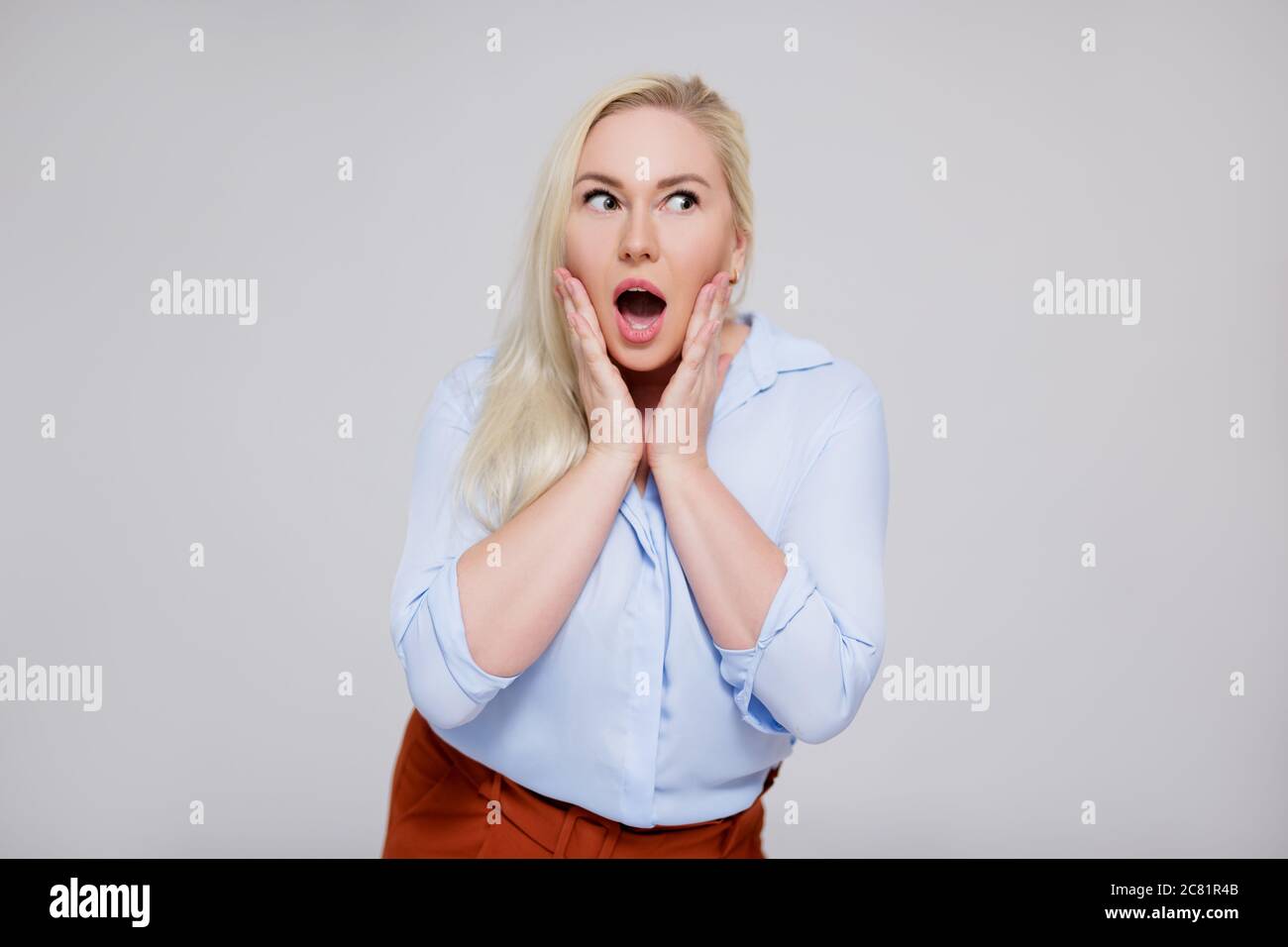 portrait of surprised beautiful plus size blonde woman over gray background with copy space Stock Photo