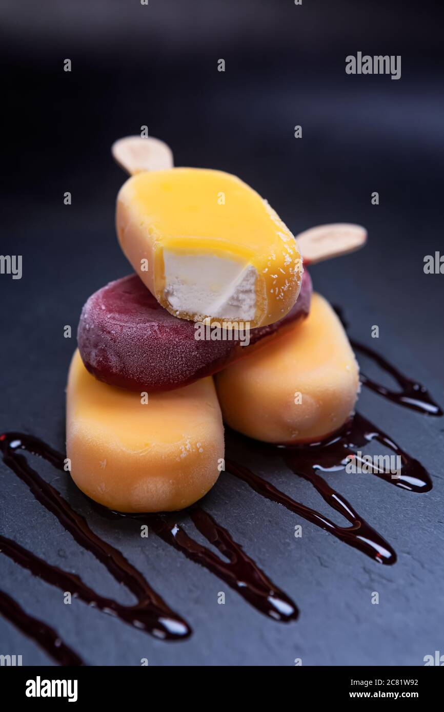 Stack of fruit ice cream stick looks fresh to eat placed on a black stone background. Stock Photo