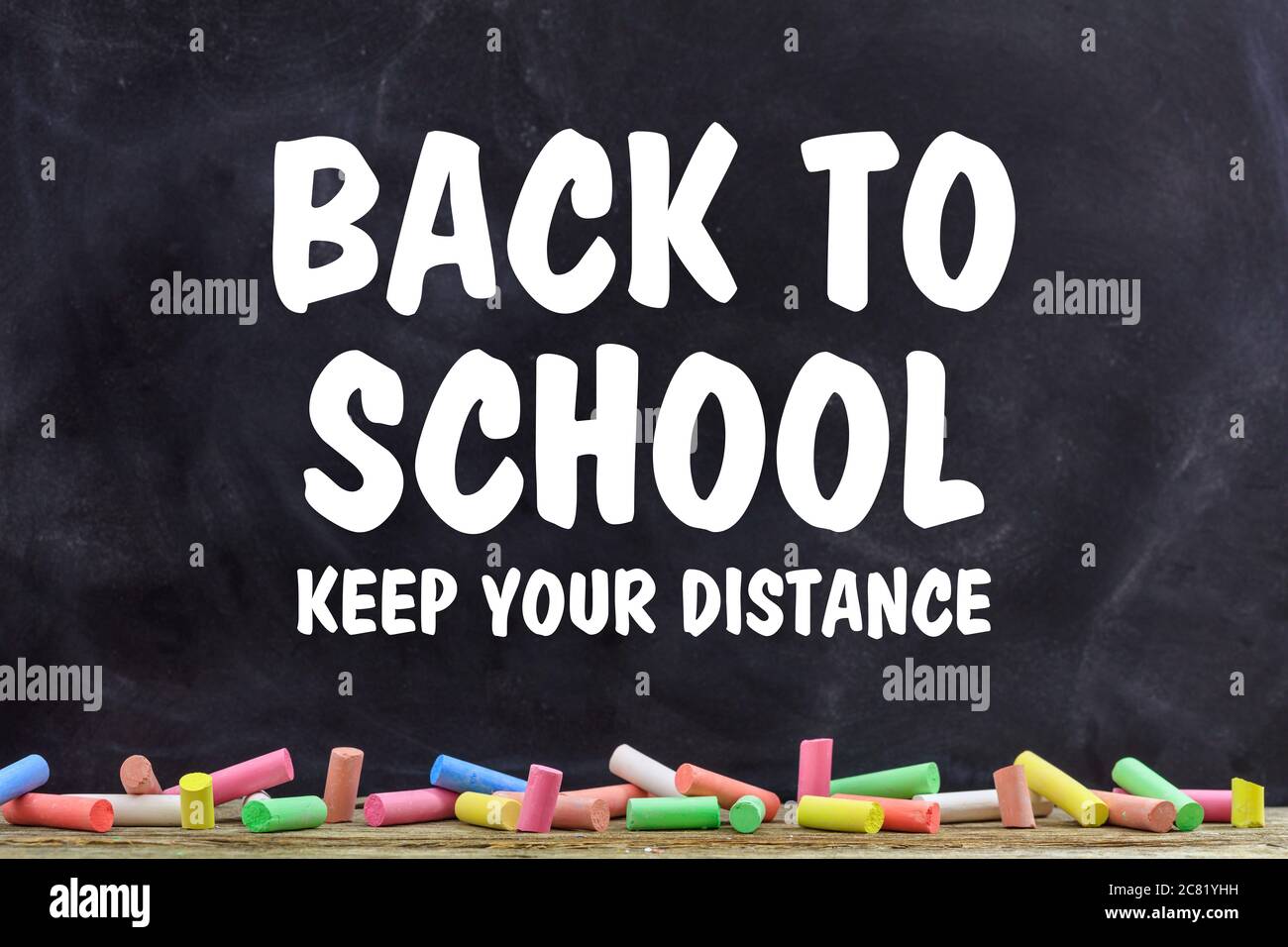 BACK TO SCHOOL KEEP YOUR DISTANCE text message against blackboard with colorful chalks background, Coronavirus spread in school prevention measure Stock Photo
