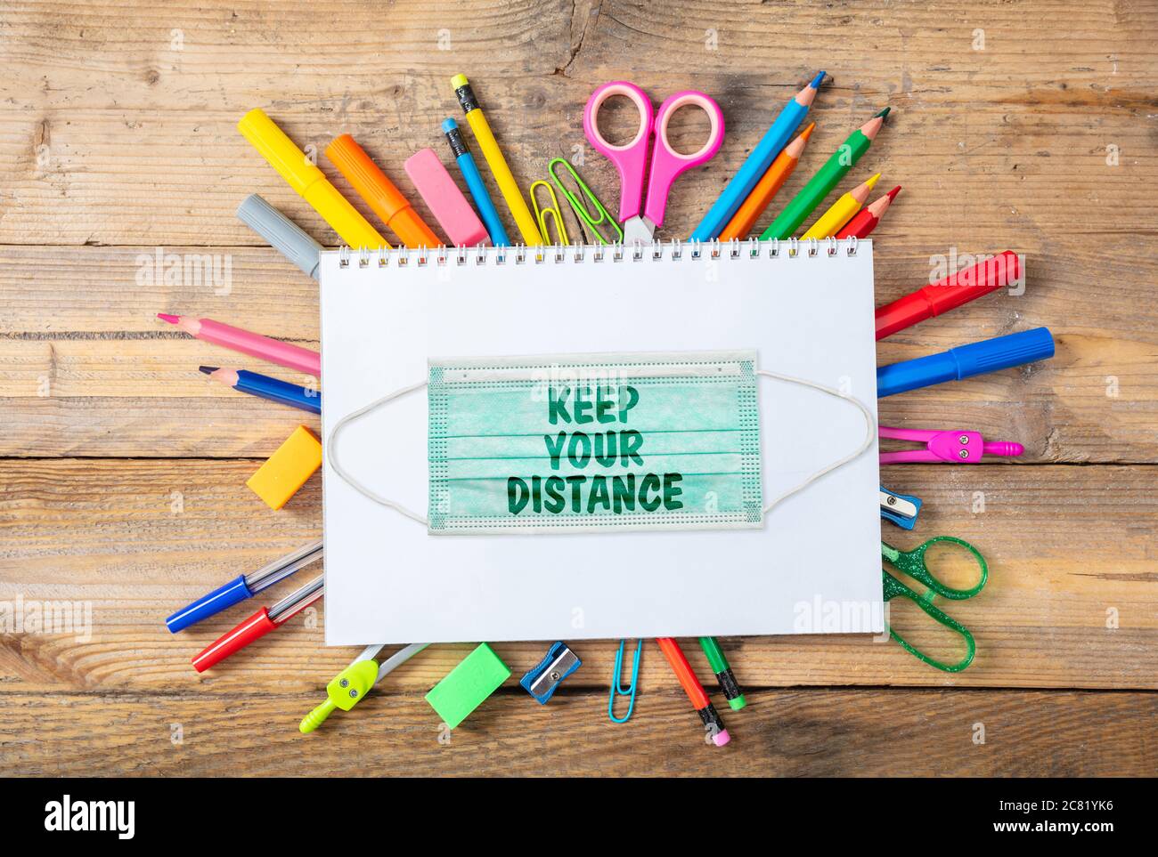 KEEP YOUR DISTANCE text message on a medical protective mask, school supplies on wood, Back to school, coronavirus days Stock Photo