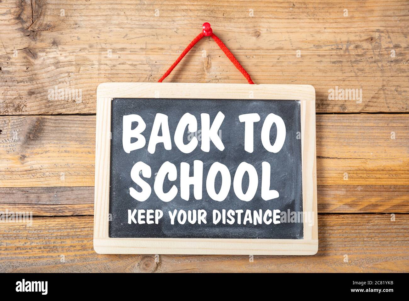 BACK TO SCHOOL KEEP YOUR DISTANCE text message on a blackboard, wooden wall background, Coronavirus spread in school prevention measure Stock Photo