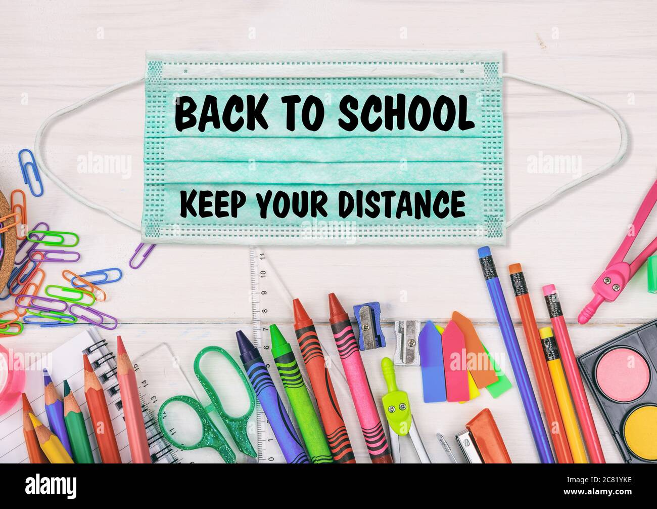 Back to school, KEEP YOUR DISTANCE text message on a medical protective mask, school supplies flat lay, School open at coronavirus days Stock Photo