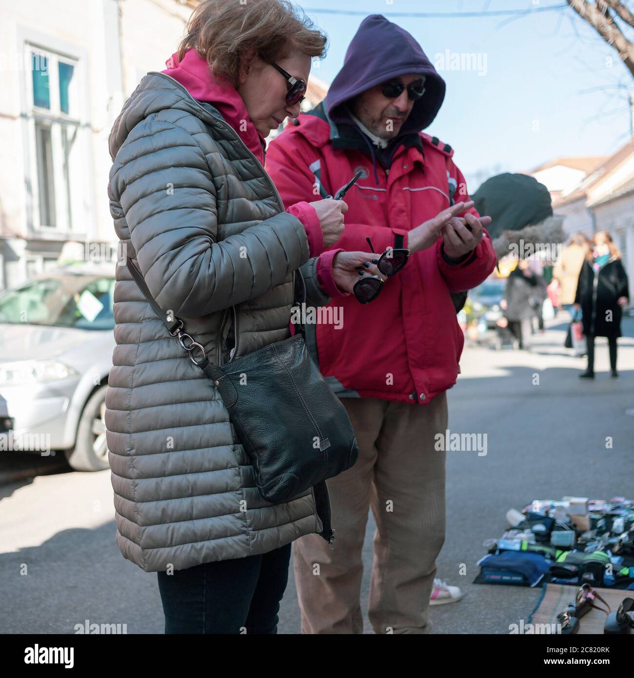 Belgrade, Serbia, Feb 22, 2020: Lady showing interest in sunglasses offered by a street vendor Stock Photo