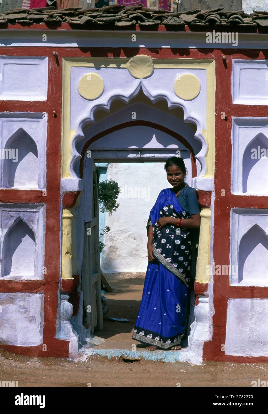 India, Rajasthan, Jodhpur, woman wearing colorful sari in front of a blue house. Stock Photo