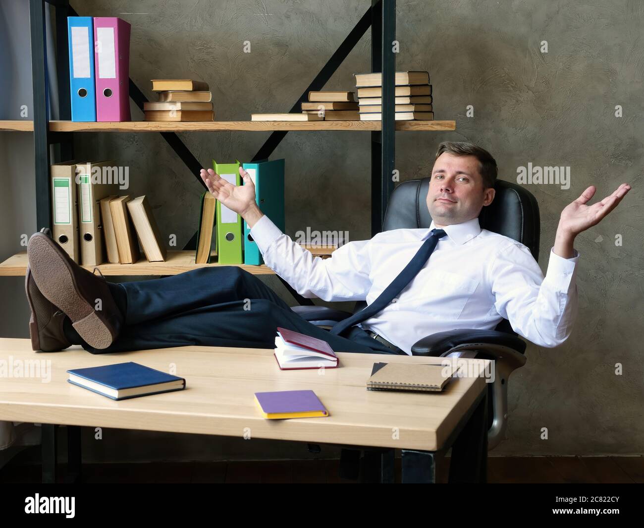 Satisfied businessman celebrates success. The man sits with his feet on the table. Stock Photo