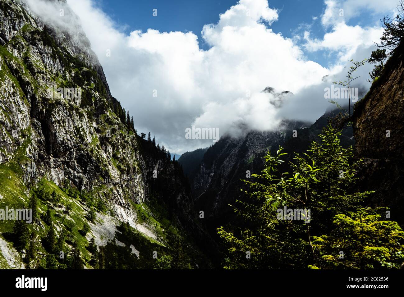 view of a valley in the alps with clouds Stock Photo - Alamy