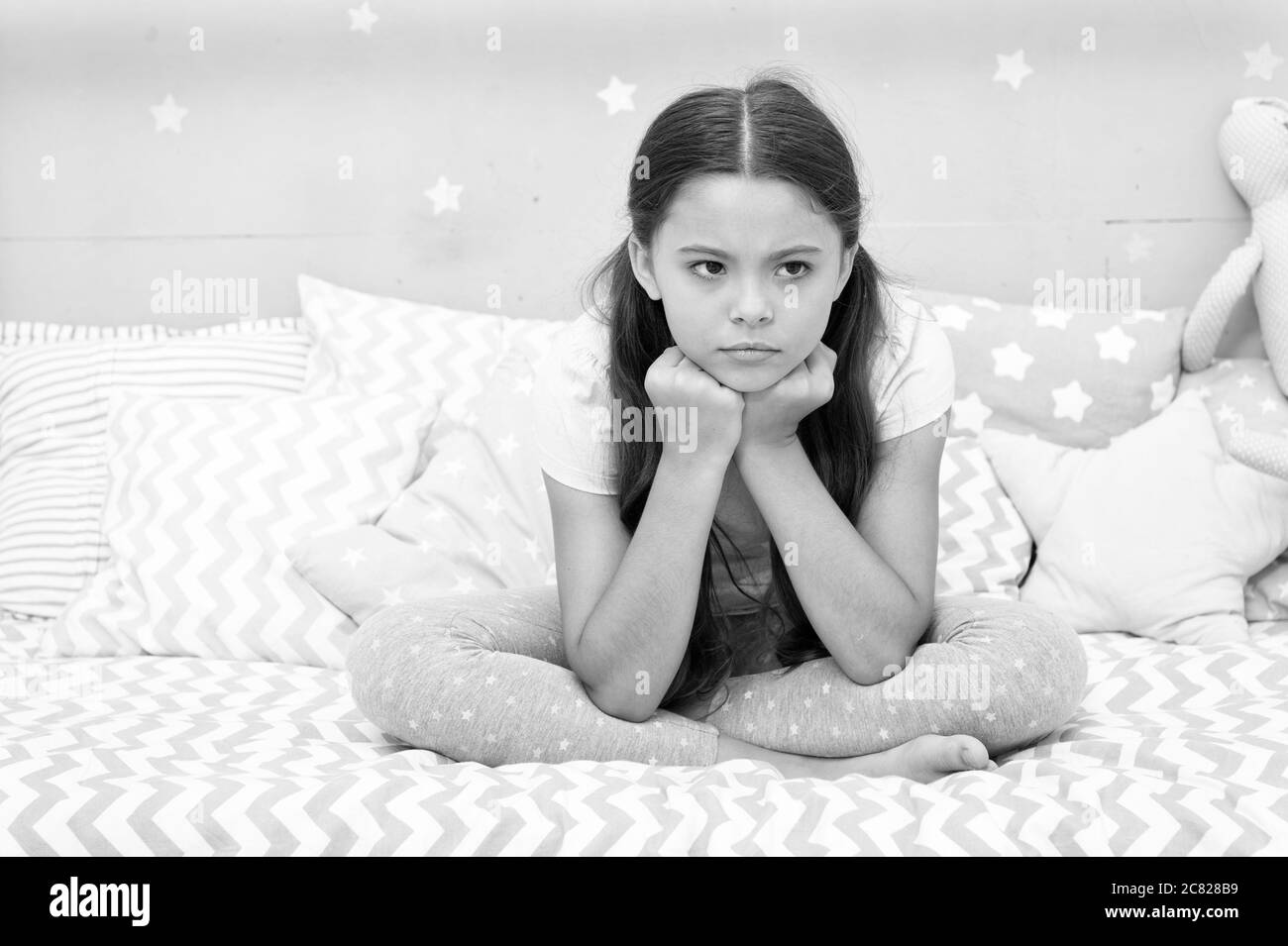 Unhappy cutie. Unhappy baby sit in bed. Little child with unhappy look ...