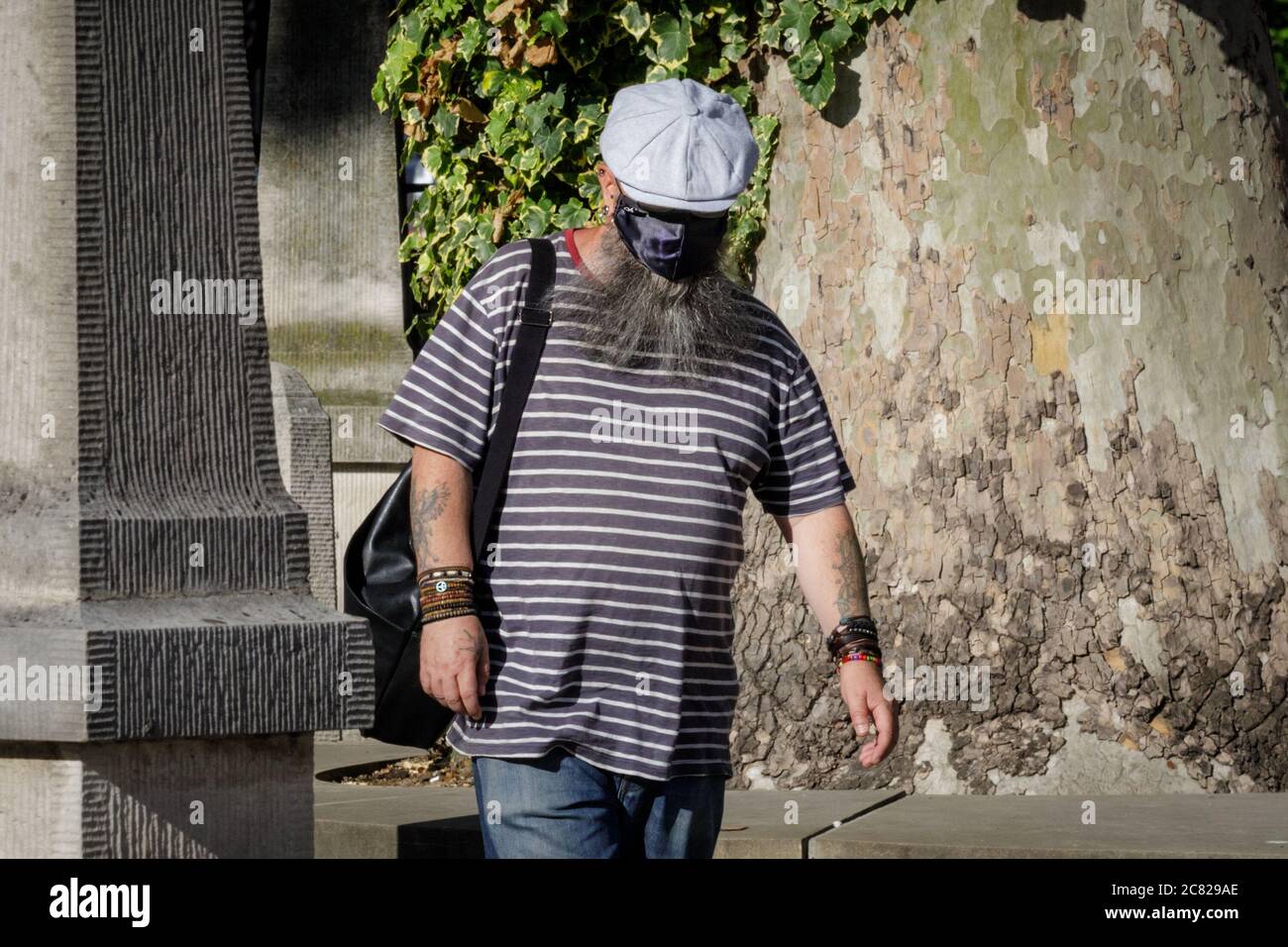 London, UK. 20th July, 2020. A man has chosen to wear his mask above a long, grey beard with an additional hat, leading to an unsusual but protective face covering and look. Face masks are becoming mandatory in more and more places in the UK and a more common sight on the streets of London. Credit: Imageplotter/Alamy Live News Stock Photo