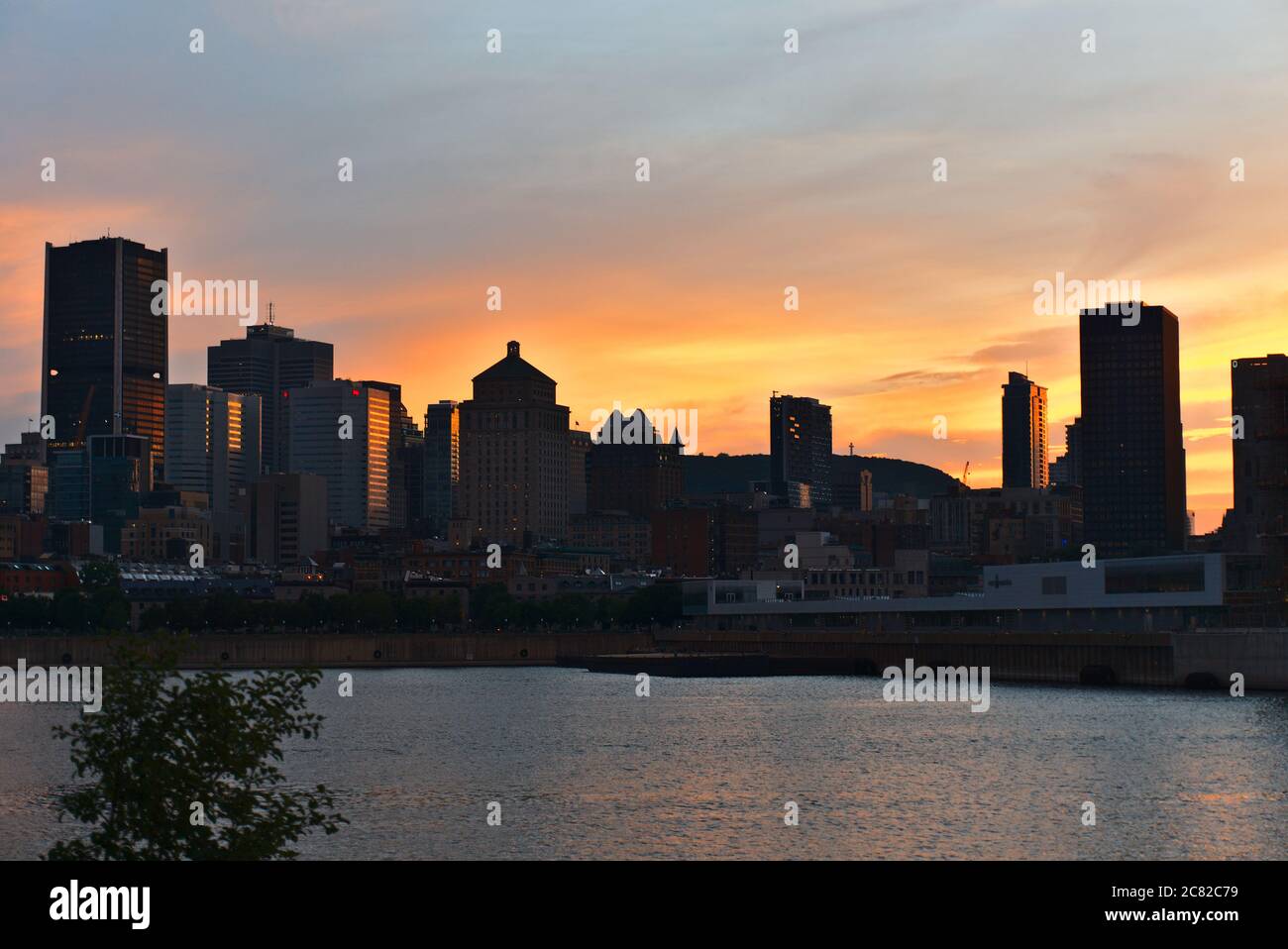 Montreal Downtown skyline at the time between sunset and twilight. Reflections of sun rays on Saint Laurent river. Stock Photo
