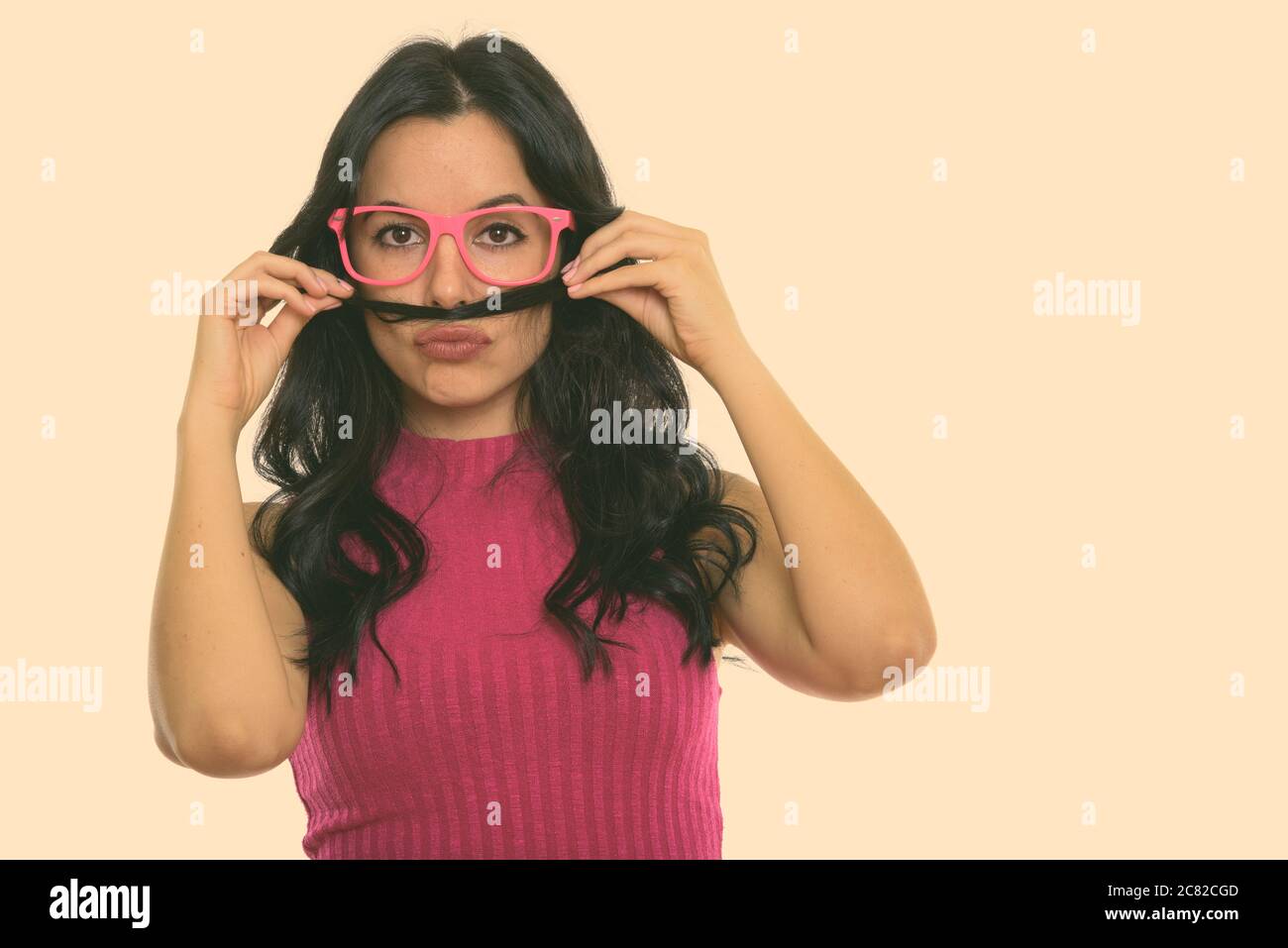 Studio shot of young beautiful Spanish woman using her hair as mustache