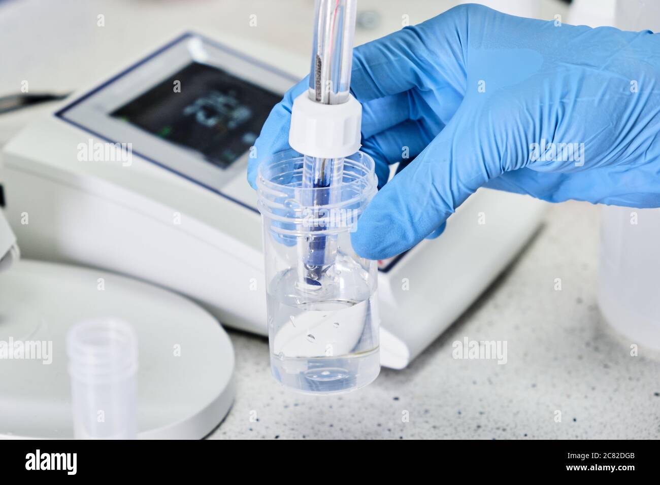 Woman in a rubber gloves holding a glass electrode for measuring of pH