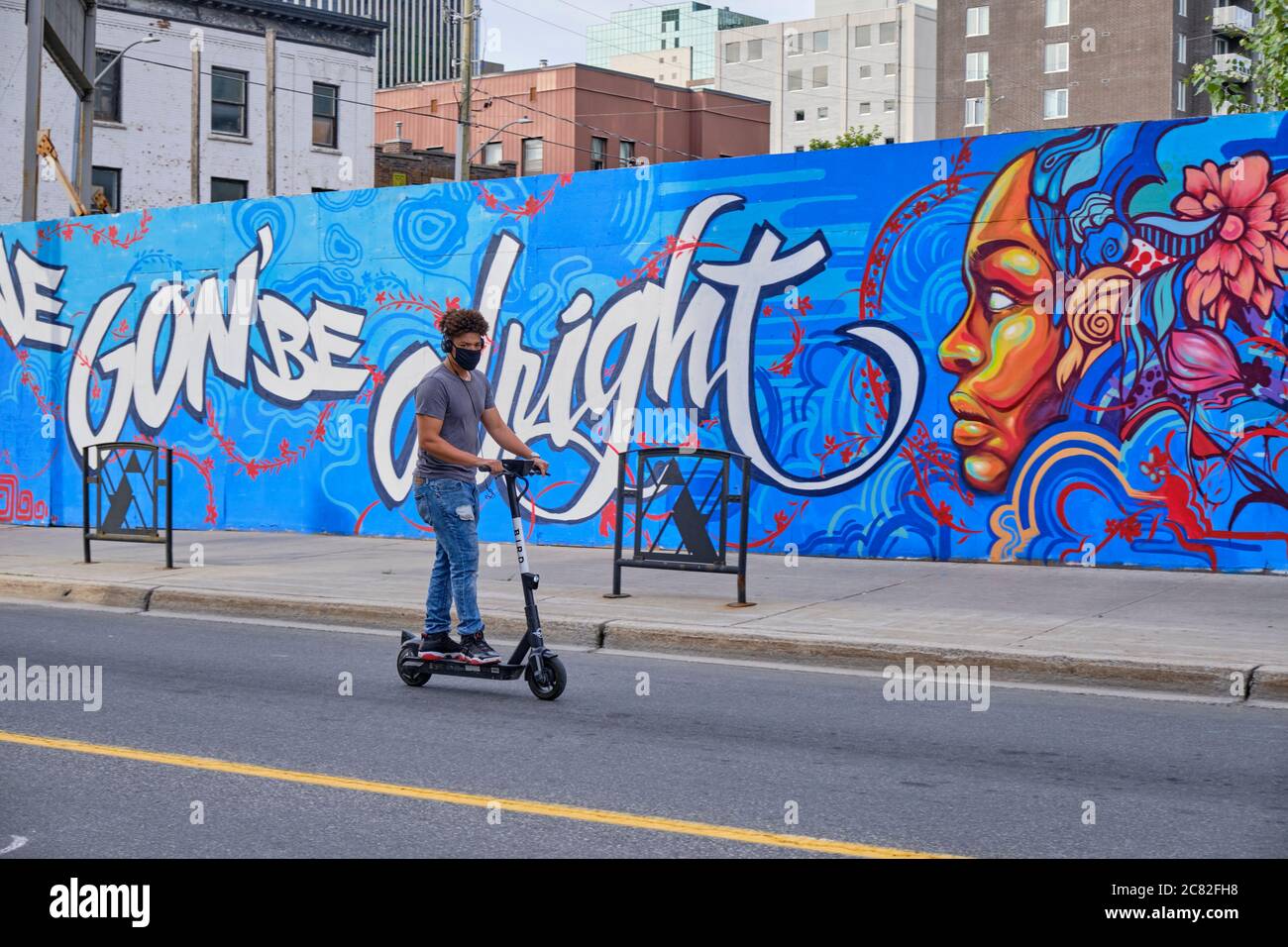 Man on electric scooted by Ottawa Wall art 'We Gon' be Alright' inspired by worldwide protests against systemic anti-Black racism; justice and police Stock Photo