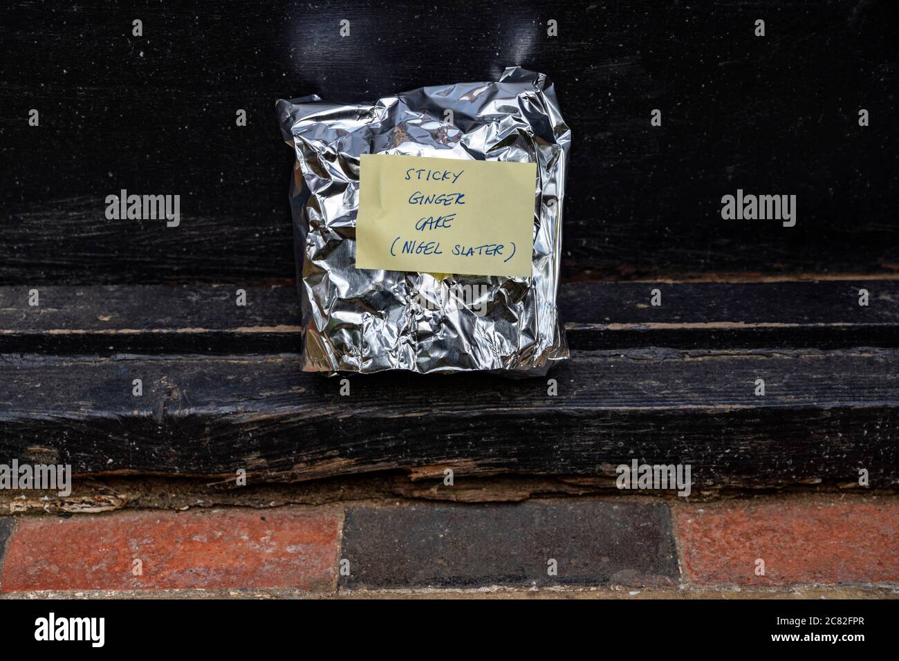 A slice of sticky ginger cake left on a doorstep Stock Photo