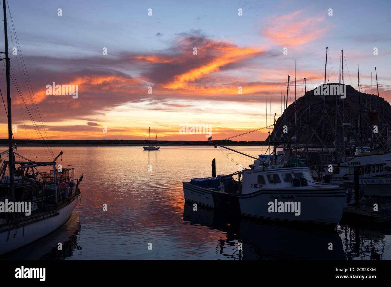 Fiery sunset reflected in Morro Bay among the fishing boats on a calm evening Stock Photo