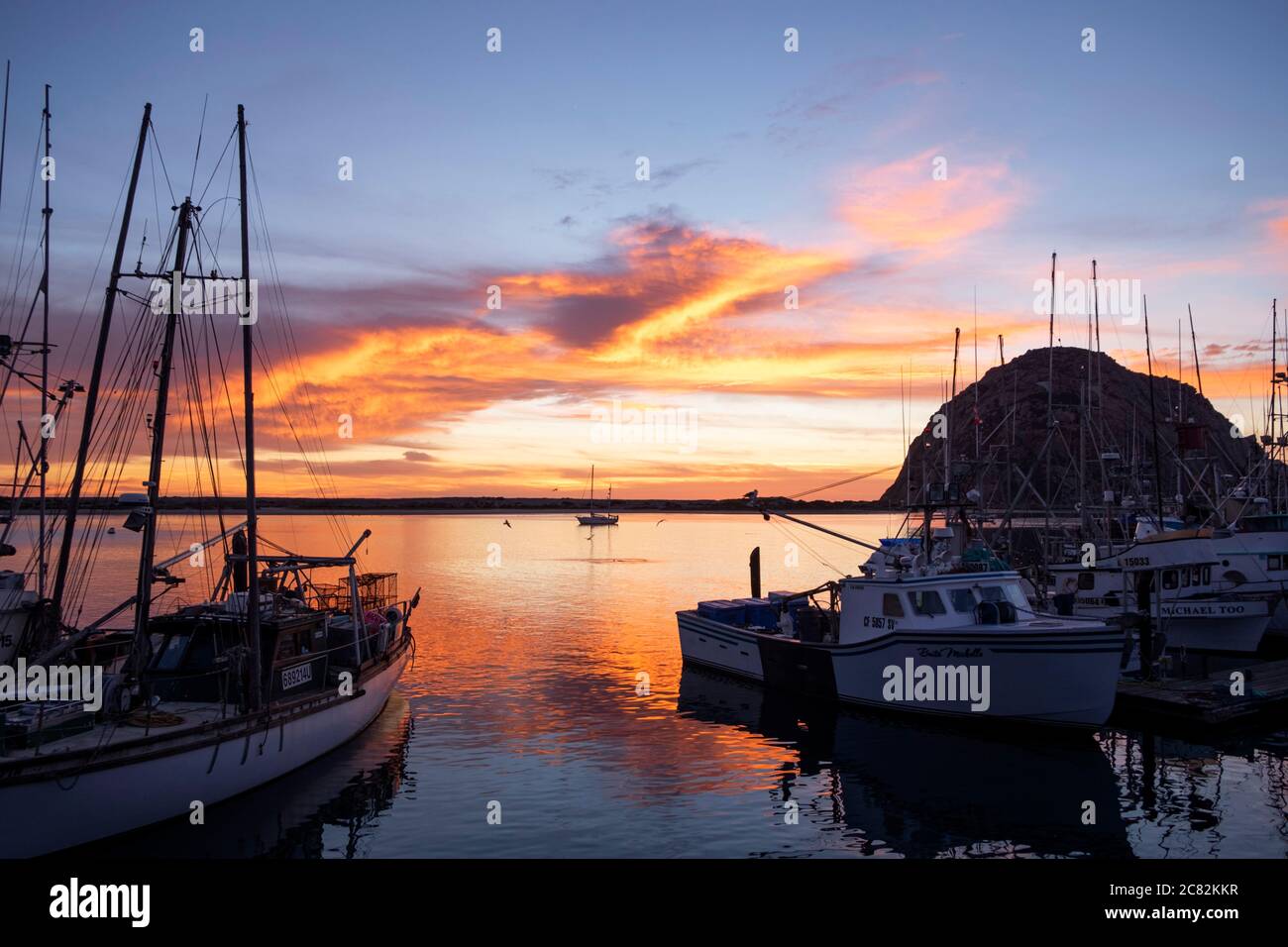 Fiery sunset reflected in Morro Bay among the fishing boats on a calm evening Stock Photo