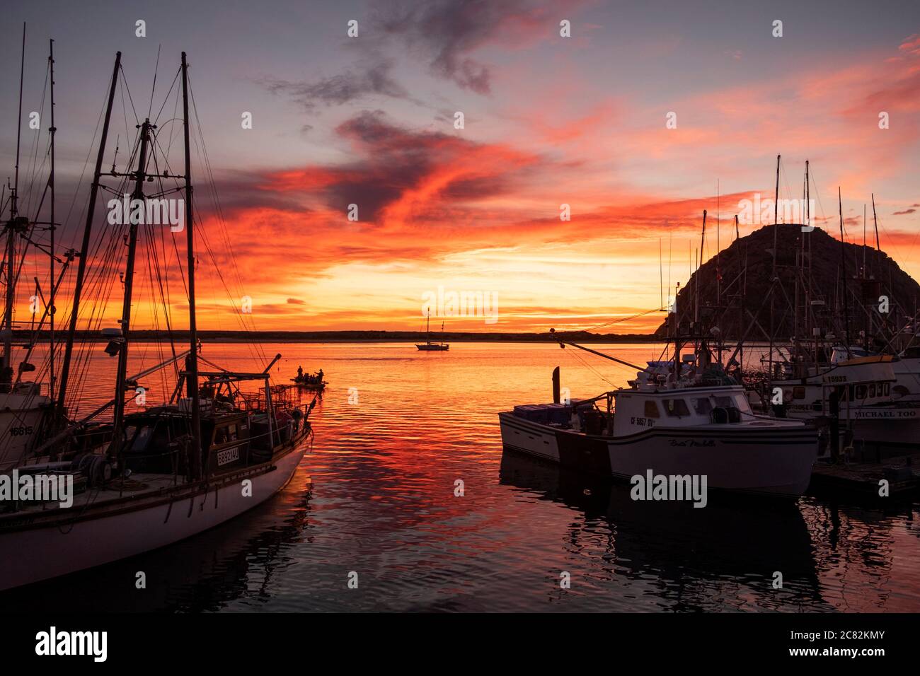 Fiery pink sky at sunset over Morro Bay marina with fishing boats in