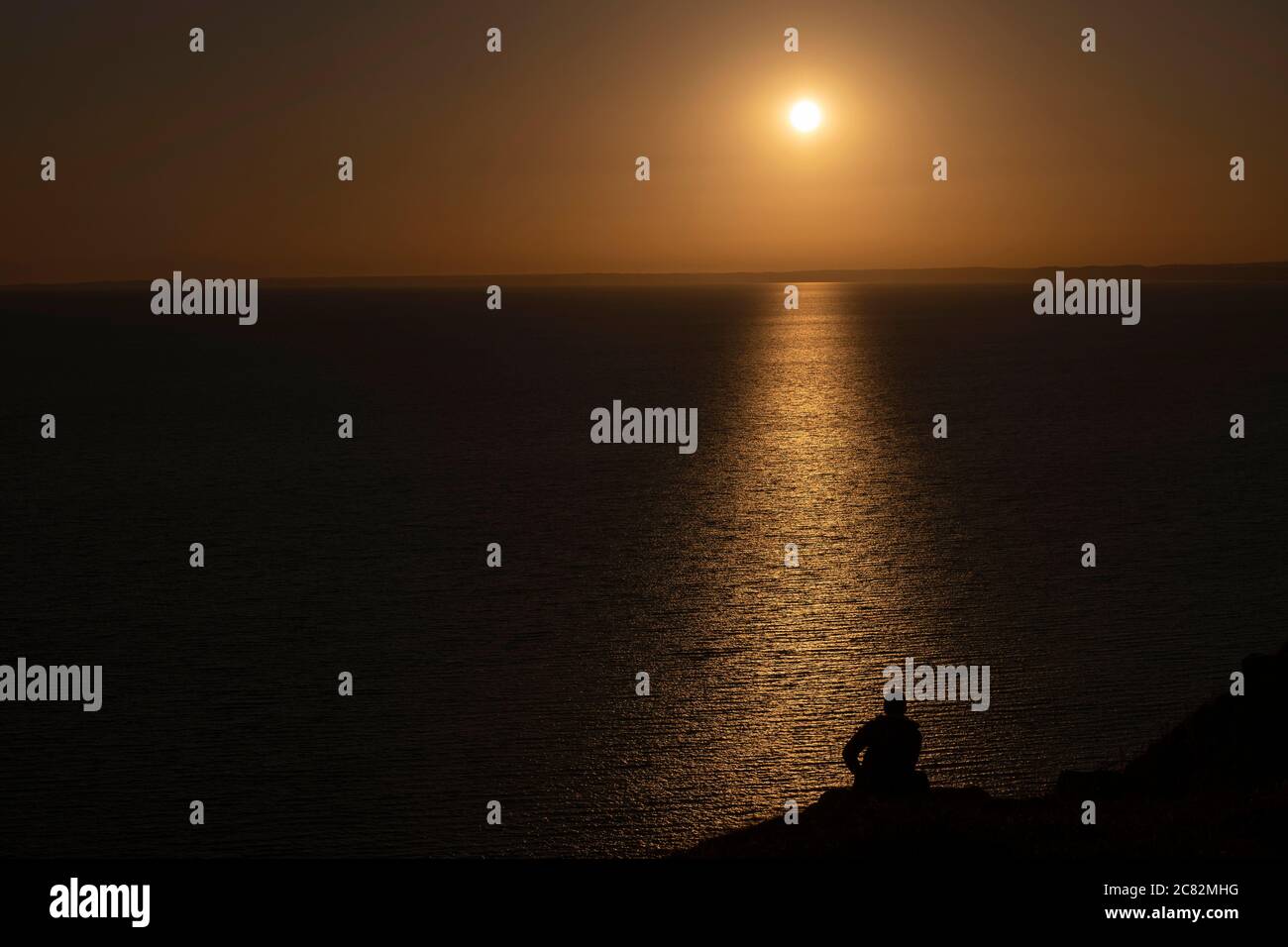 Portland, England. 20th July 2020. Silhouette of a man watching the setting sun over West Bay on the Isle of Portland in England. The Isle of Portand is in the county of Dorset. (photo by Sam Mellish / Alamy Live News) Stock Photo