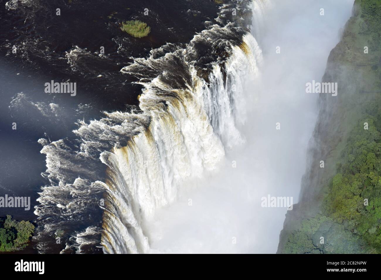 An aerial view of the Zambezi River flowing over the edge of Victoria Falls into the first gorge. Zimbabwe & Zambia. Stock Photo