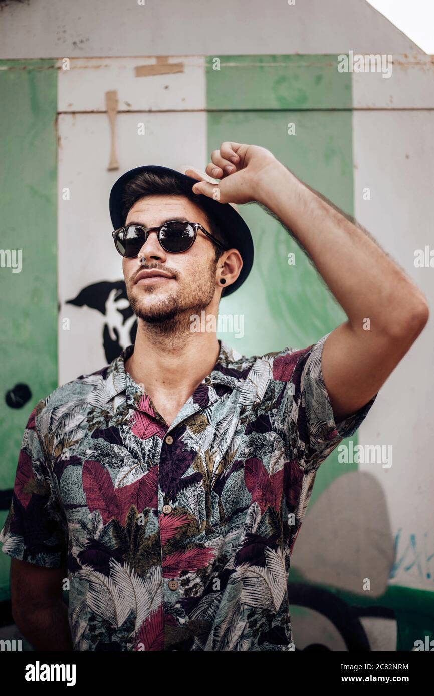 Handsome young guy with sunglasses touching his hat Stock Photo Alamy