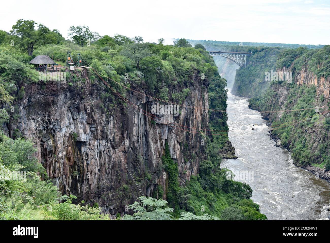 The second gorge formed by the Zambezi River.  Victoria Falls Bridge can be seen spanning the gorge.  Ropes cross the river for zip lining. Stock Photo