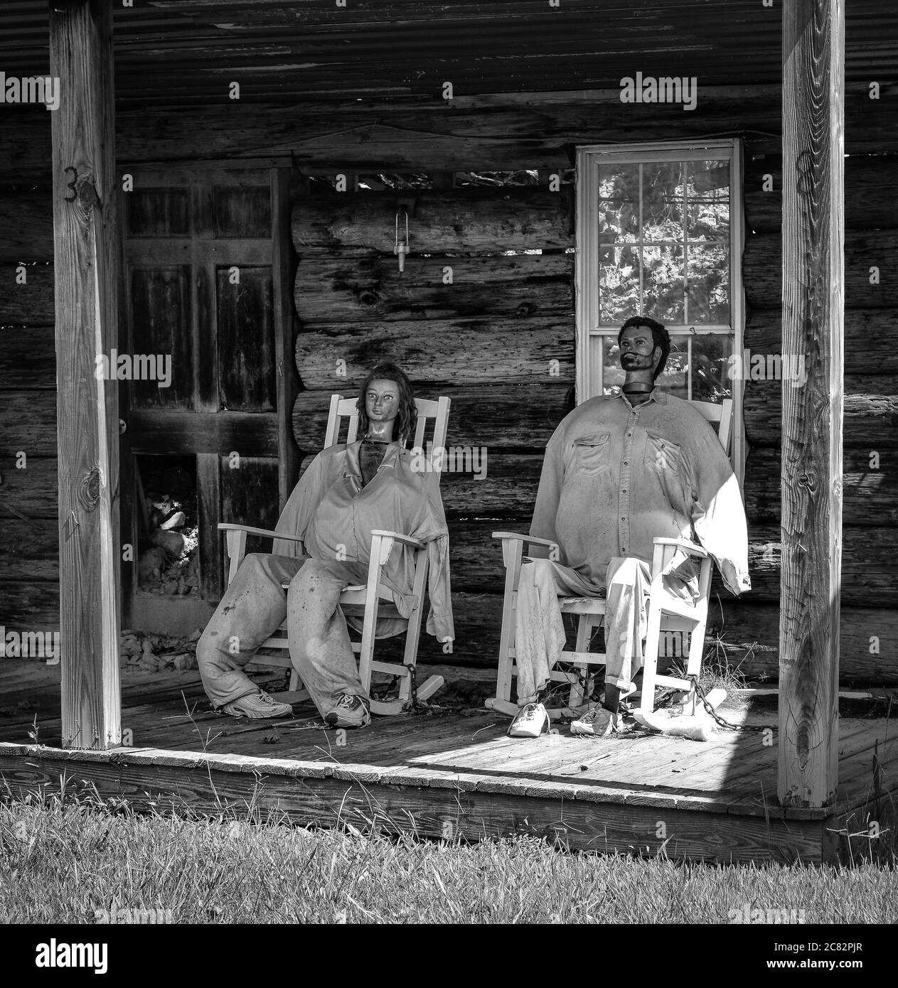 A male and female mannequin head each with stuffed bodies in rocking chairs on front porch of fake cabin at Fake Town, in rural middle TN, USA, Stock Photo