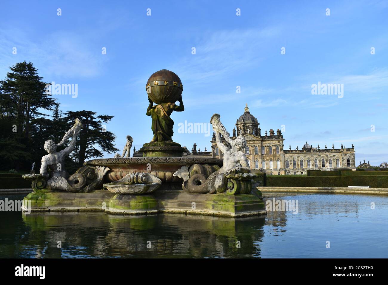 The Atlas Fountain in front of the South Front of Castle Howard in North Yorkshire, England. Reflections of the house and fountain in the water. Stock Photo