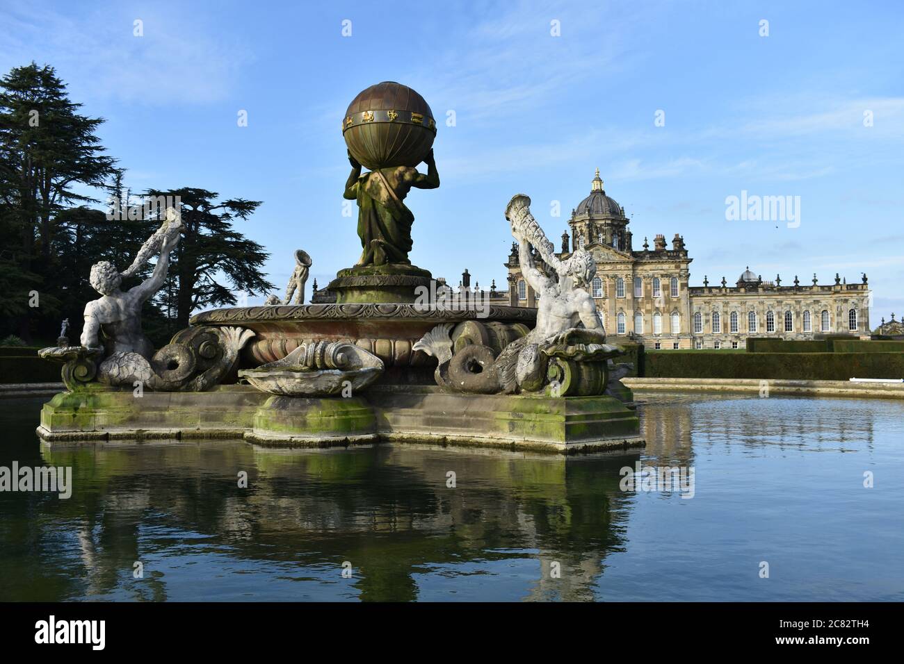 The backside of the Atlas Fountain in front of the South Front of Castle Howard in North Yorkshire. Reflections of the house and fountain in the water Stock Photo