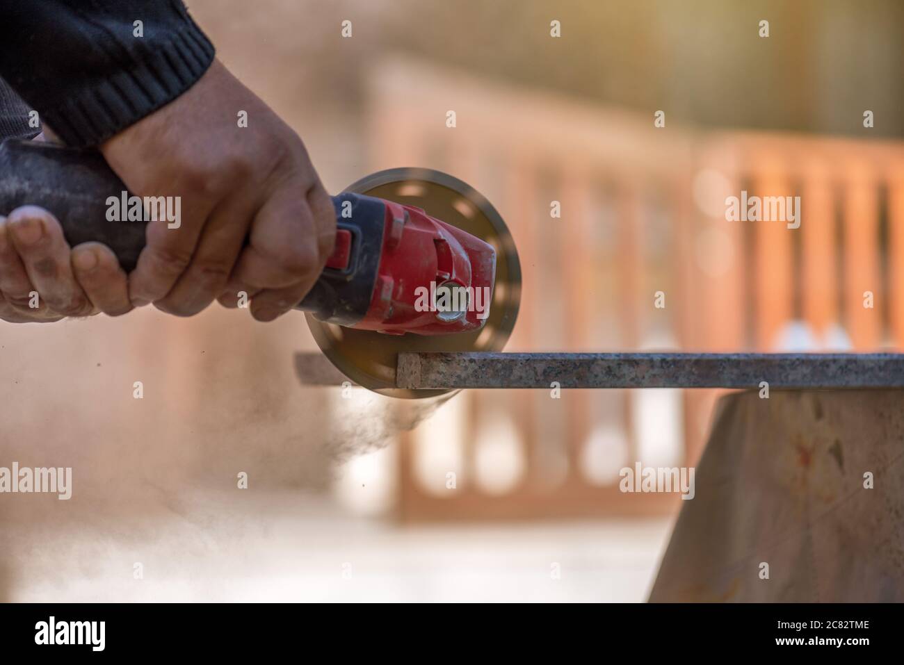 Grinder worker cuts stone block with electric hand saw. Stock Photo