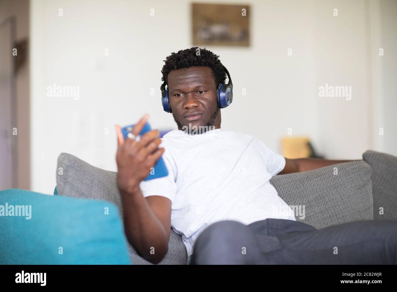 young black man sitting on a couch at home hearing music Stock Photo