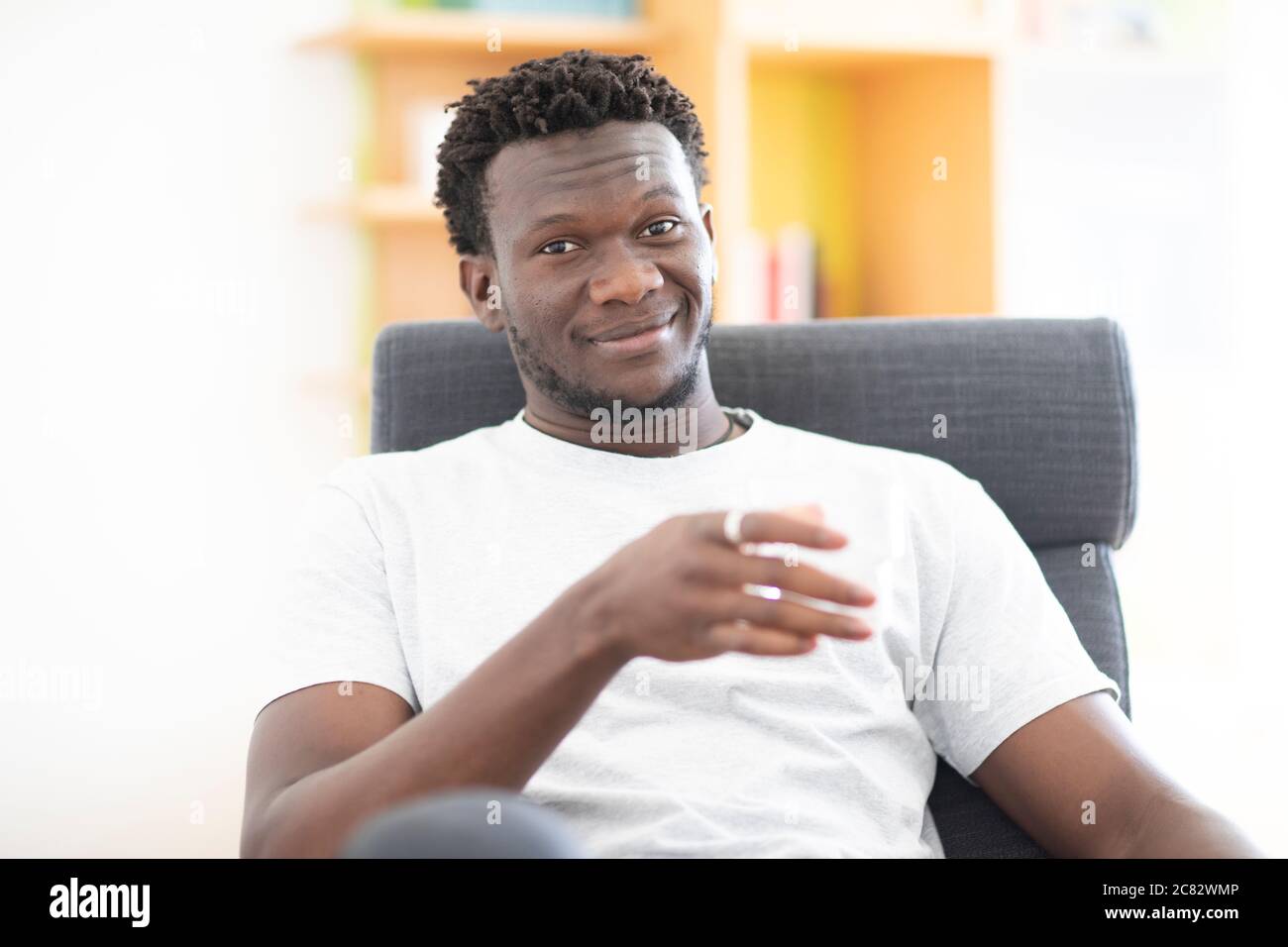 young man at home sitting  in an arm chair Stock Photo