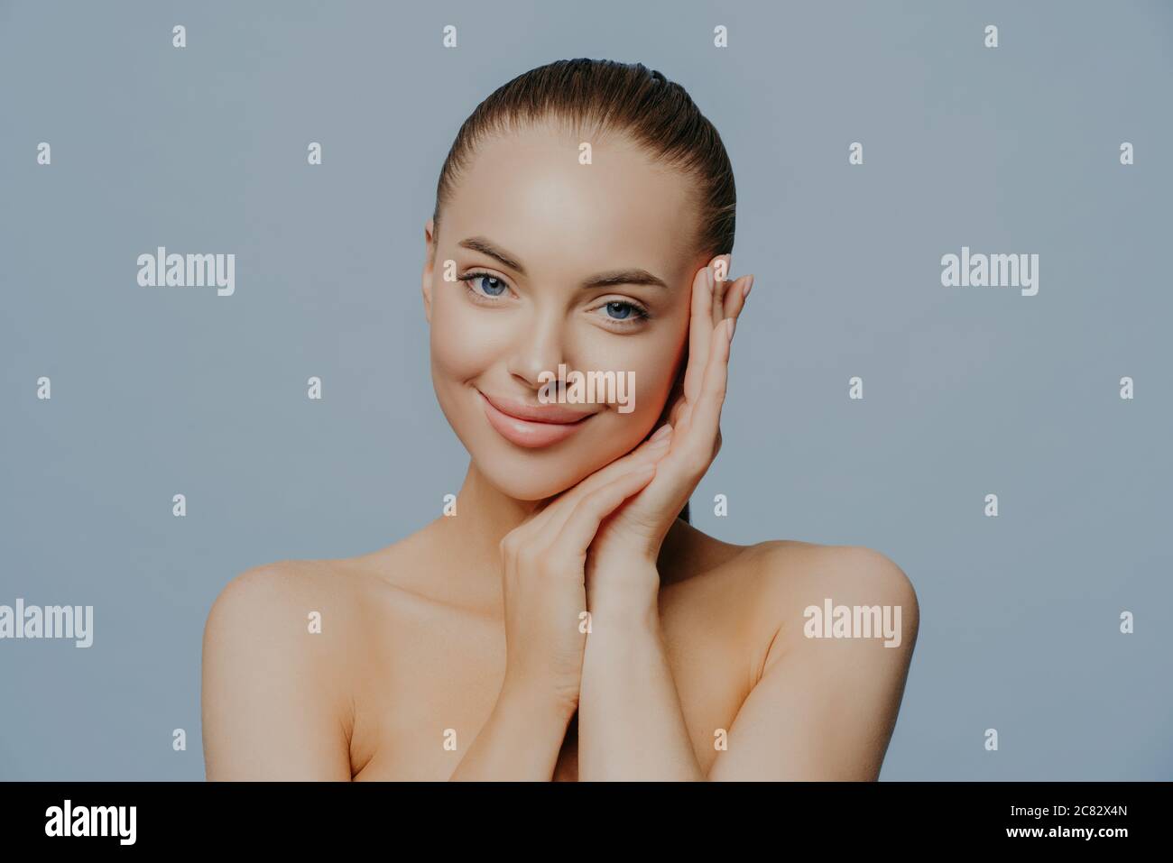 Beauty woman face portrait. Beautiful spa model girl with perfect fresh clean skin on blue background. Brunette female looking at camera. Youth and sk Stock Photo