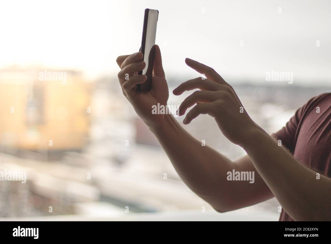Man using his smartphone against a bright window Stock Photo