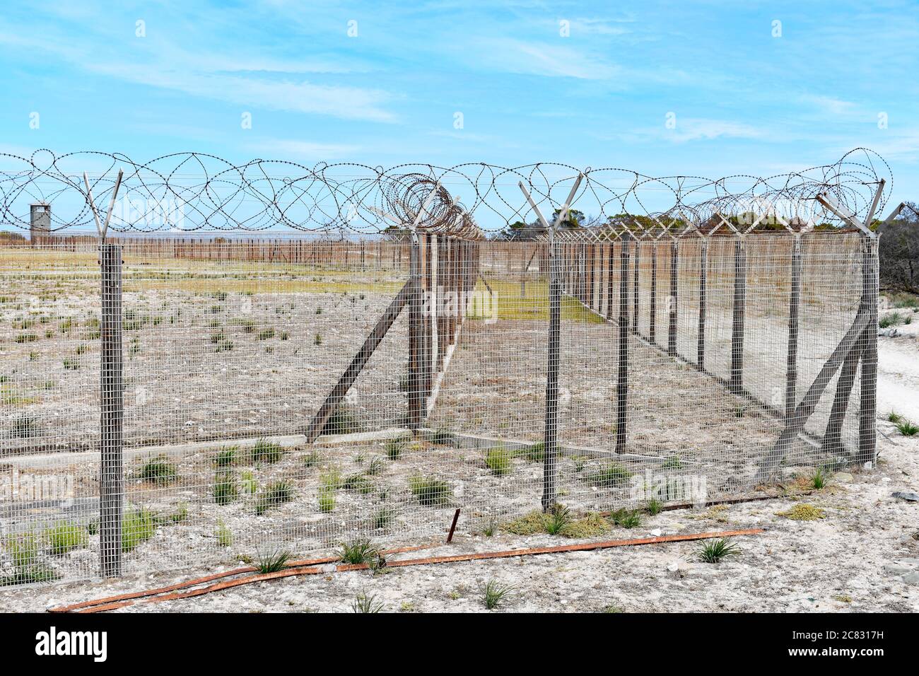 The security fences of the former high security prison on Robben Island.  Barbed wire lines the top of the fence.  Cape Town, South Africa. Stock Photo