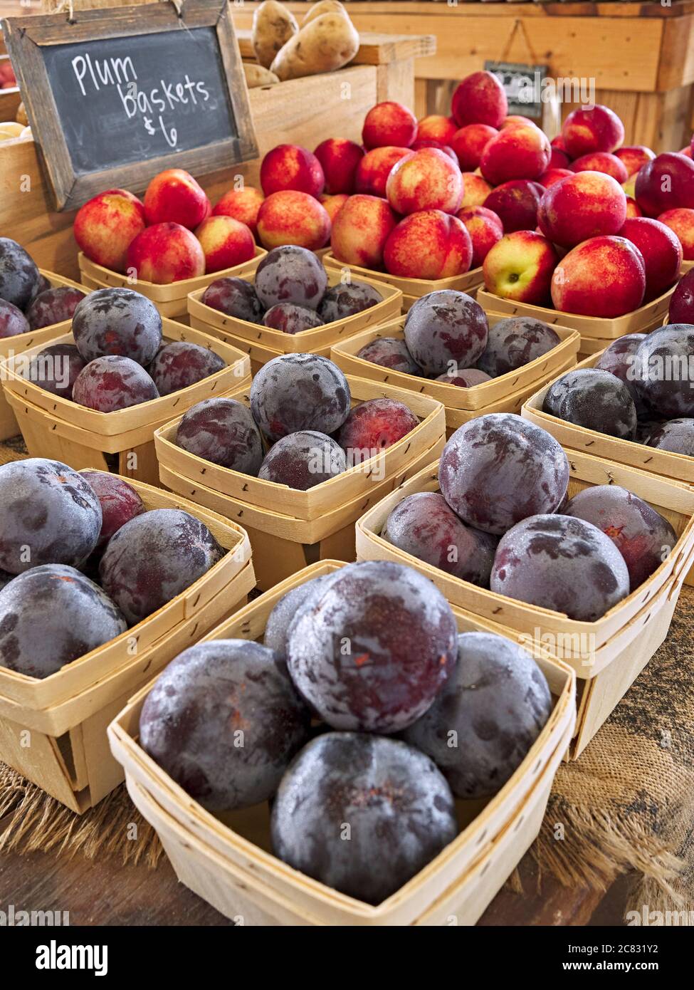Plums, apples and other fresh fruit on display at a farm or farmers market. Stock Photo