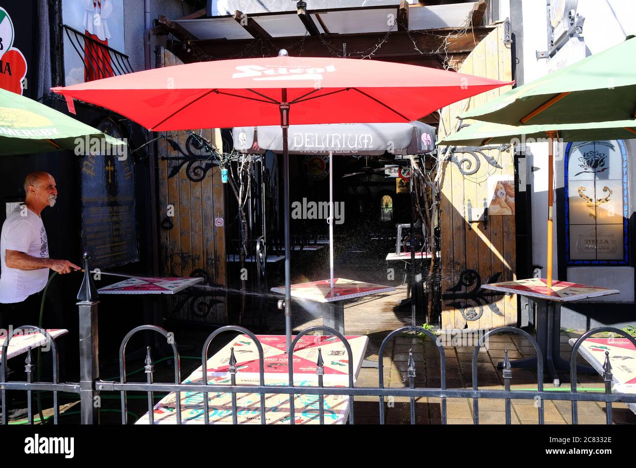 Restaurateur hosing down outdoor restaurant patio distanced tables as