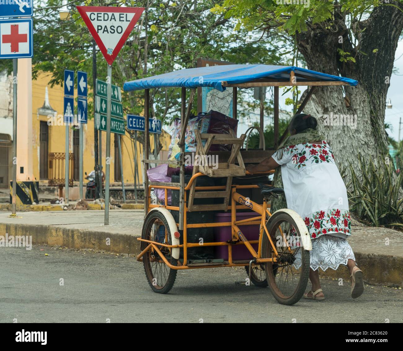 A Mayan woman in her traditional embroidered huipil pushes her cargo  tricycle with her wares for the market in Muna, Yucatan, Mexico Stock Photo  - Alamy