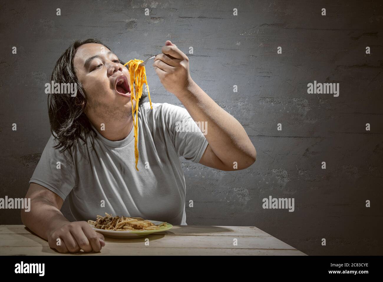 Asian man eating spaghetti at home. Junk food concept Stock Photo Alamy