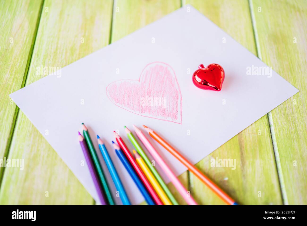 Closeup shot of a red heart drawing on a white paper with colored ...