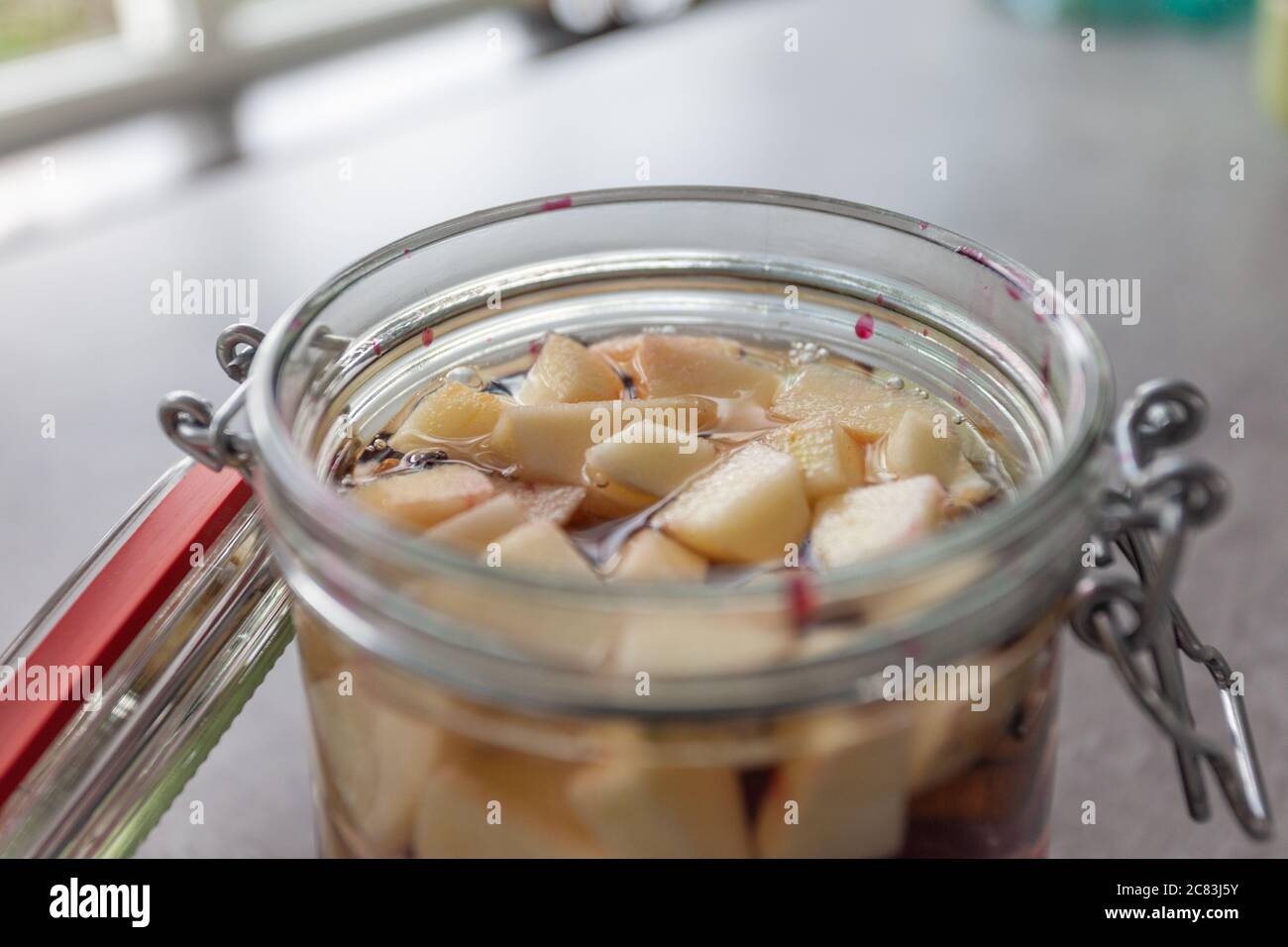 Closeup shot of a glass bank with cut fruits on a grey table Stock Photo