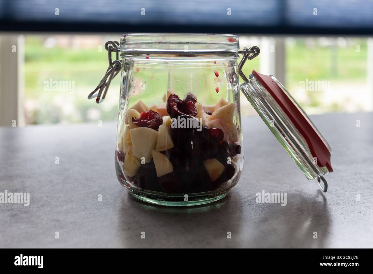 Closeup shot of a glass bank with cut fruits on a grey table Stock Photo