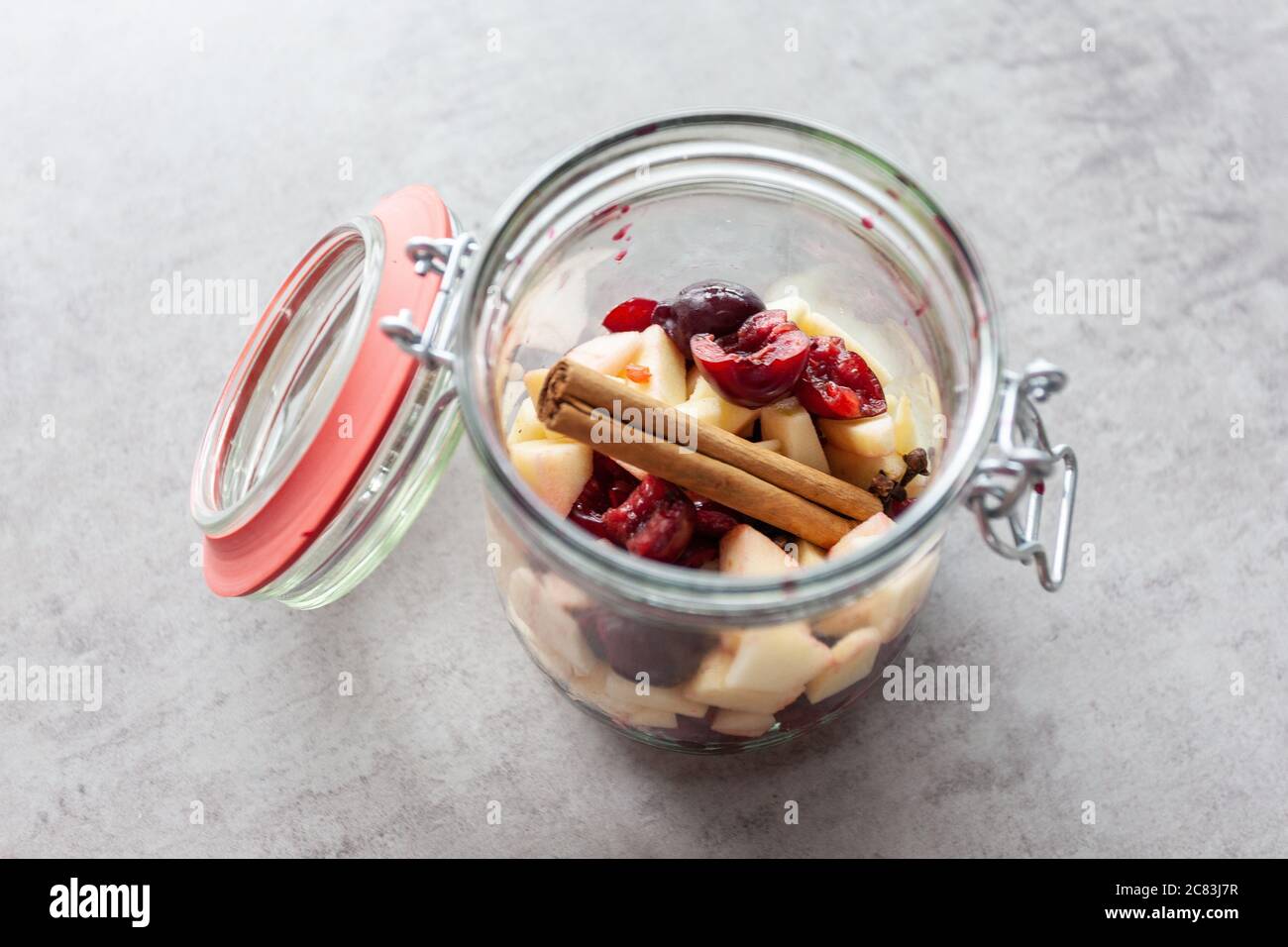 Closeup shot of a glass bank with cut fruits on a grey table Stock Photo