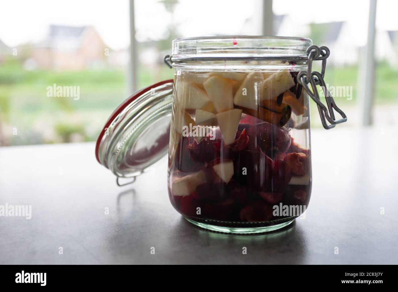 Closeup shot of a glass bank with cut fruits on a grey table Stock Photo