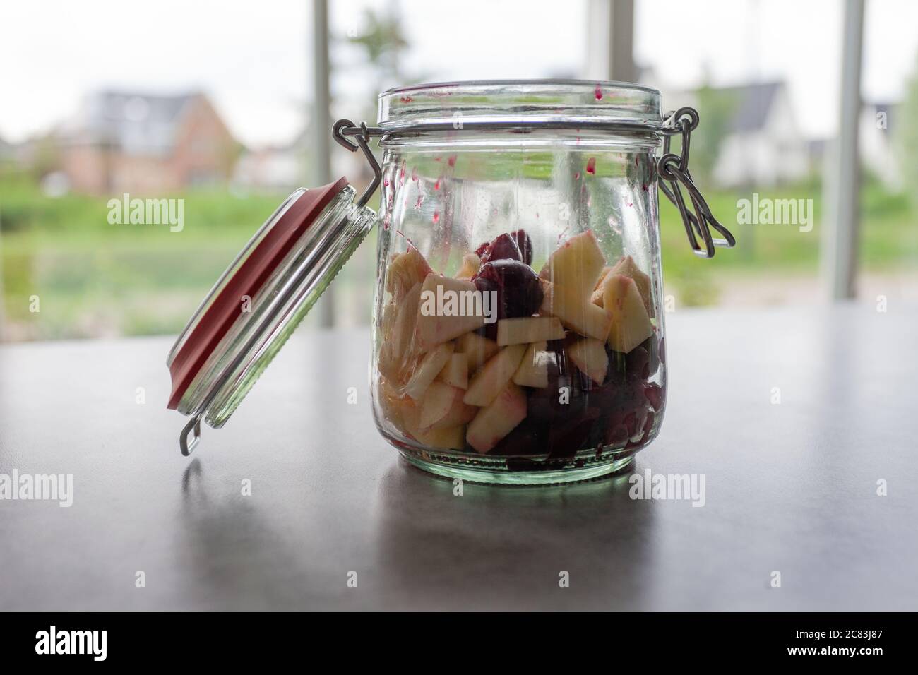 Closeup shot of a glass bank with cut fruits on a grey table Stock Photo