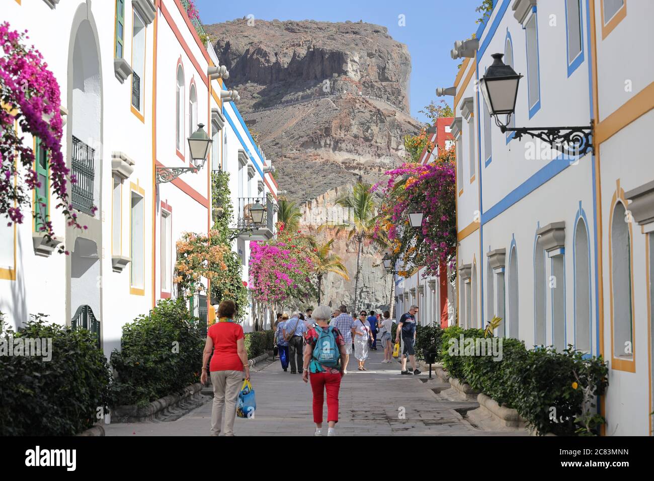 Mogan,Gran Canaria,02.06.2019.Typical street with multi-coloured bougainvillea plants and shops in the Harbour of Mogan Stock Photo