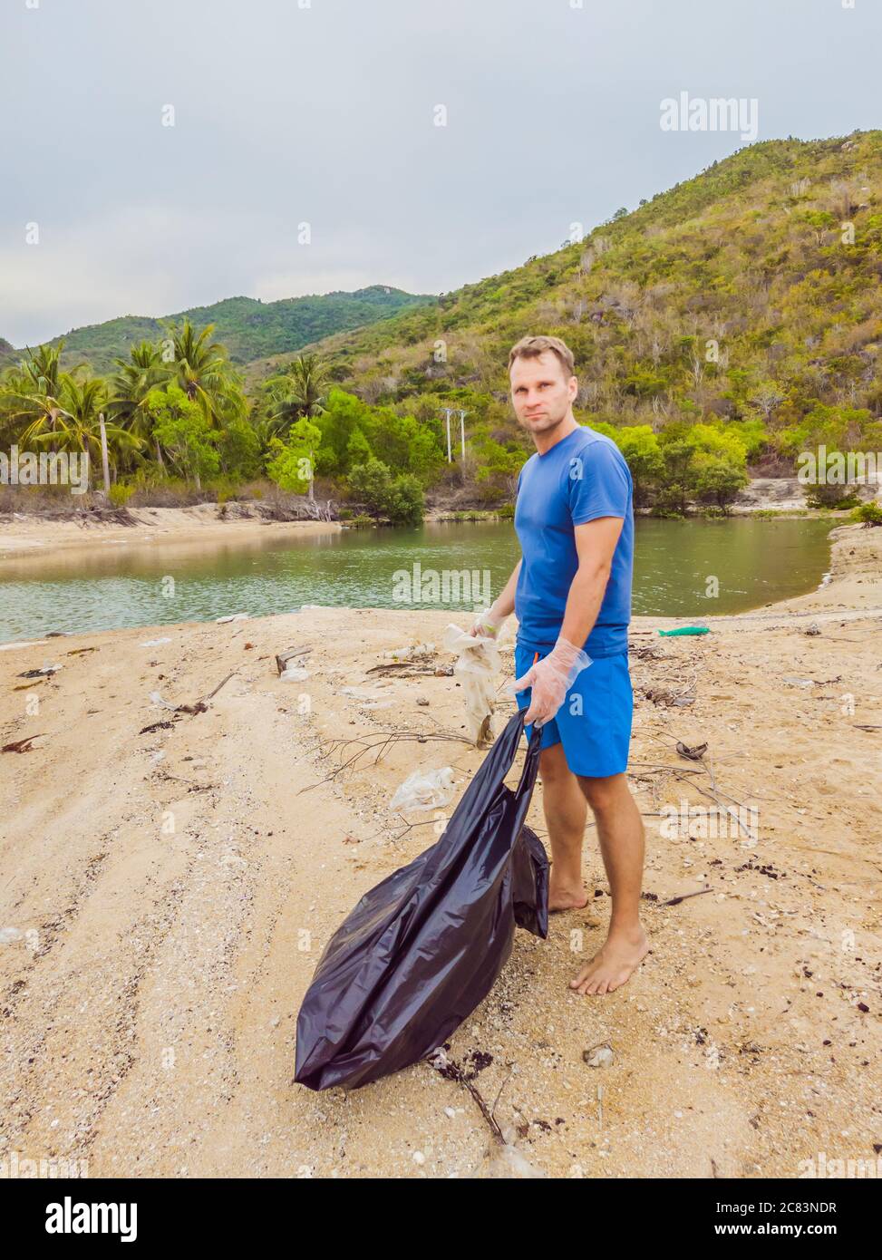 Man in gloves pick up plastic bags that pollute sea. Problem of spilled