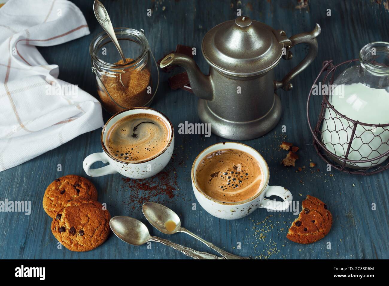 Family breakfast - two cups of coffee with milk espresso and homemade oatmeal cookies with chocolate on a blue wooden vintage table, rustic style, low Stock Photo
