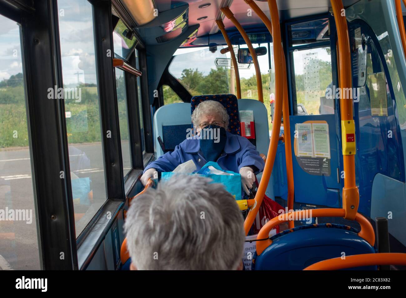 People wearing face masks sitting on a bus journey sit apart during